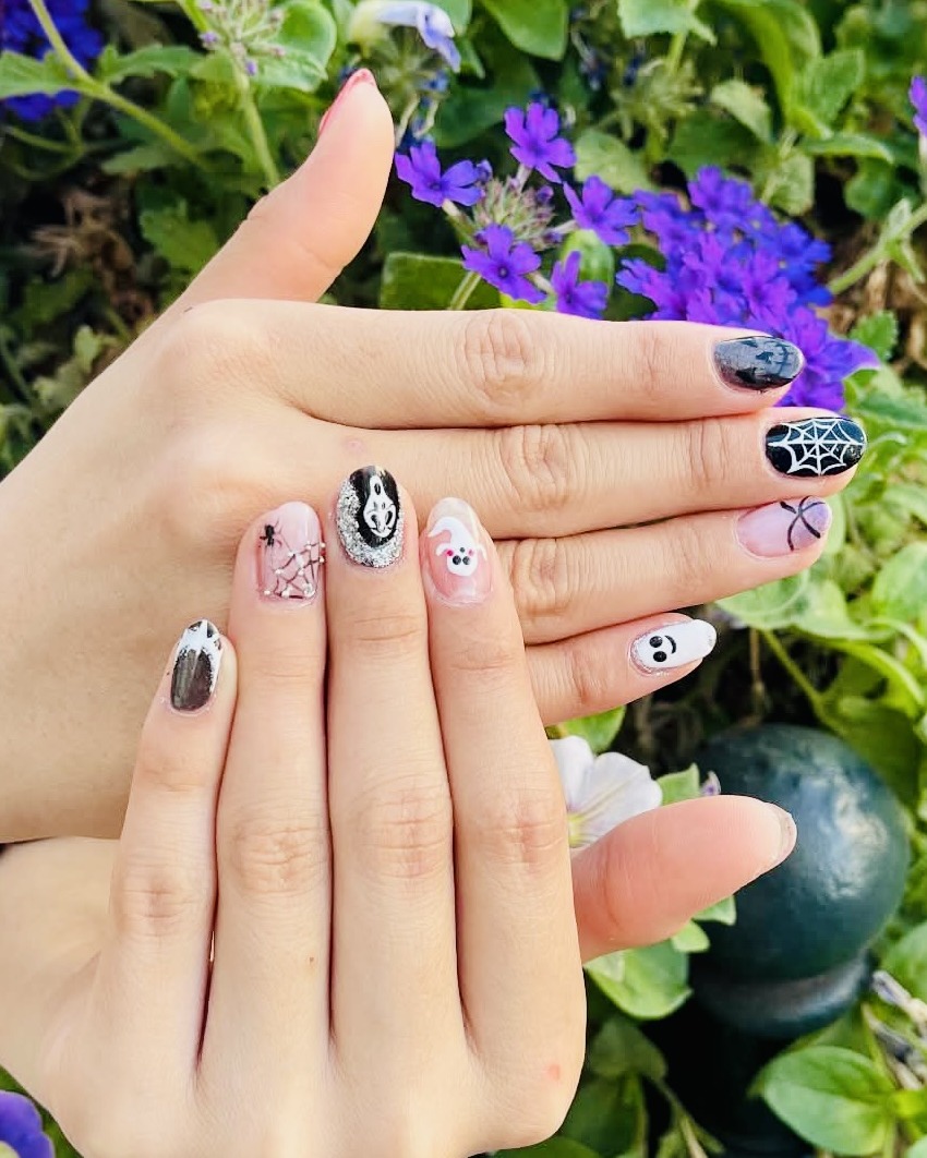 Nail art Halloween peint à la main : toile d'araignée, fantôme et petits motifs sur base nude et noire