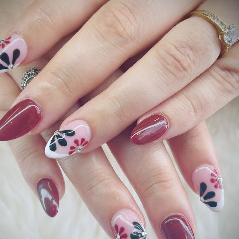 Burgundy and white French tips with painted flowers and rhinestones