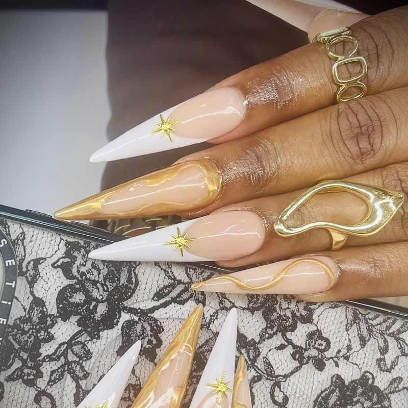 Stiletto nails with white French tips and gold swirls